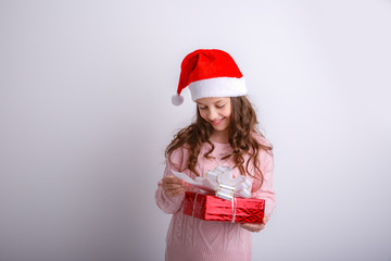 smiling little girl in Santa hat with gift in hand on isolated white background