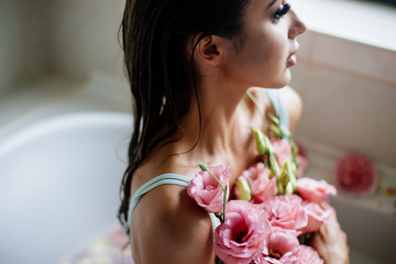 Beautiful girl in the bathroom with many flowers.