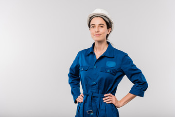 Pretty young successful female engineer in blue workwear and safety helmet