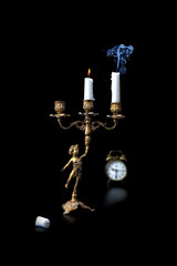 Fototapeta na wymiar a photo of a candlestick, clock and burning candles symbolizes the transience of life.