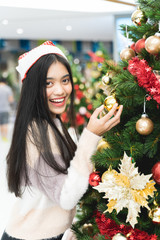 Happy Asian Women wearing Santa hats are decorated Christmas tree before the day of Christmas.