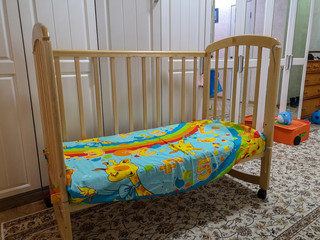 A wooden cot with a bright colored sheet standing in the middle of the corridor