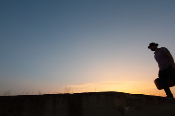 silhouette of man with suitcase at sunrise