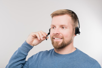 Young cheerful hotline operator in headset and blue pullover consulting clients