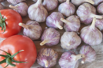 Fresh harvest of garlic and tomatoes on wooden table. Organic food concept