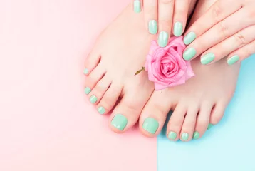 Wall murals Pedicure Female hands, legs with manicure and pedicure with flower on a pink, blue background, top view