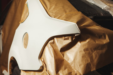 Body repair of the car after the accident. Wraping of vehicle with protective paper before painting.
