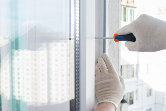 gloved hands adjust a new installed window with a screwdriver, closeup