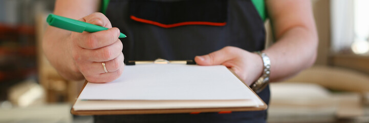 Arms of worker offer clipboard with green pen