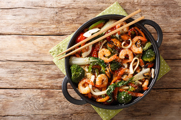 Tasty recipe for stir fry seafood with fresh vegetables close-up in a pan. horizontal top view