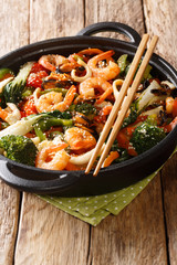 stir-fried shrimp, squid and mussels with fresh vegetables close-up in a pan. vertical