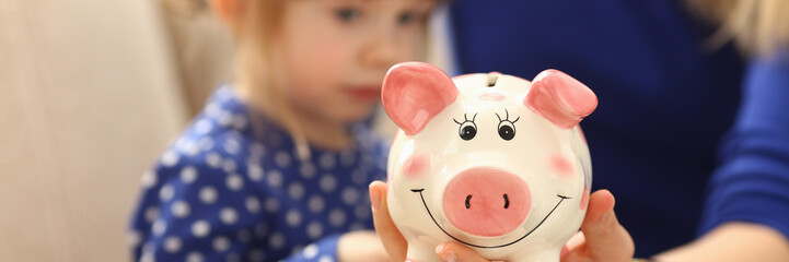 Child little girl arm putting coins into piggybank