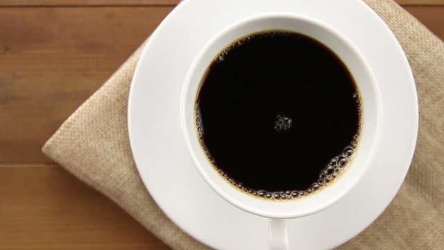 Top View Of Stirring Black Coffee In White Cup On Wooden Table