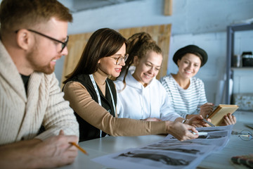 Young creative designers discussing fashion sketches while working in studio
