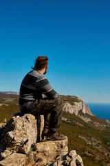 A man sitting on a top of a mountain