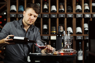 Sommelier pouring red wine from bottle in glass