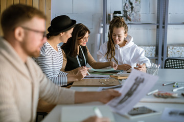 Fototapeta premium Group of happy young women discussing creative ideas while working in studio