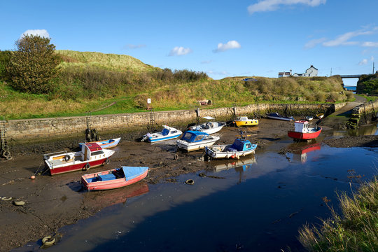 Fishing boats at low tide at the coastal village of Seaton Sluice harbour in Northumberland.