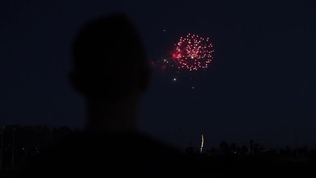 Blurred closeup silhouette of a man enjoying fireworks at night