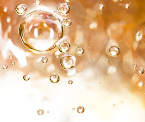 Bubbles of air on the smooth surface of golden water as an abstract background
