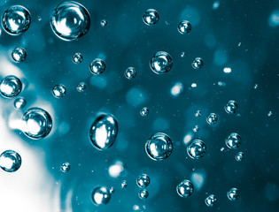 Bubbles of air on the smooth surface of blue water as an abstract background
