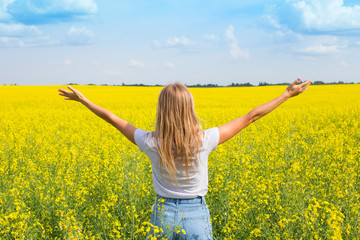 Naklejka premium The girl spread her arms while standing with her back in the field. Wish fulfillment concept