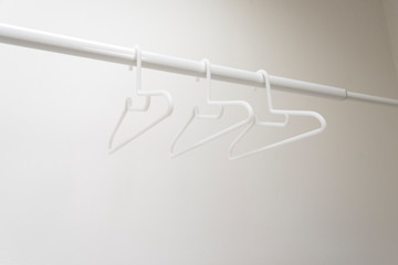 物干し竿とハンガー　白いハンガー　アップ　クローズアップ　洗濯　物干し　室内干し　イメージ　一人暮らし　暮らし　家事　生活　花粉　梅雨　室内　屋内　背景　背景素材　グラフィック素材　グラフィック背景　余白　ホワイトスペース　文字スペース　コピースペース