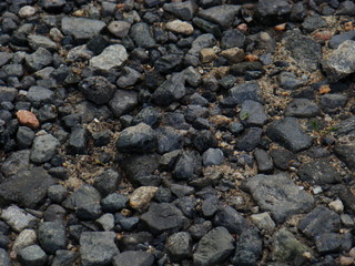 Big stones on a sandy beach. Boulders of gray and brown on the sand.