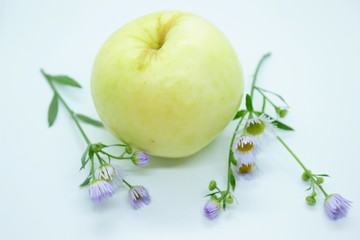 Green apple and daisies are located on a white background