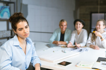 Obraz premium Sad or pensive young female student sitting by workplace in studio