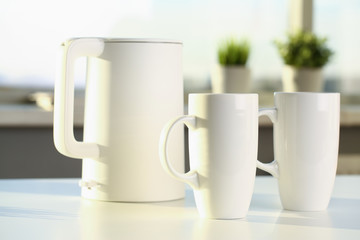 Teapot and two trendy cups are on the table for