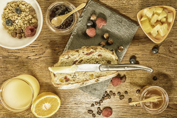 Petit déjeuner varié avec pain aux fruits secs et céréales jus d'orange frais miel salade de fruits et fruits rouges avec un bol de céréales et un couteau à beurre pour tartiner confiture