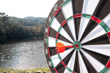 Dart arrow hit on bulleyes of dartboard with water background, Planning new business target and goals