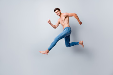 Fototapeta na wymiar Full size profile photo of crazy macho man guy jumping high running topless torso metrosexual hot body competitive mood wear only jeans isolated grey background