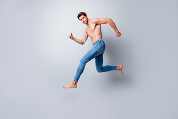 Fototapeta na wymiar Full size profile photo of focused macho man guy jumping high running topless torso metrosexual hot body competitive mood wear only jeans isolated grey background