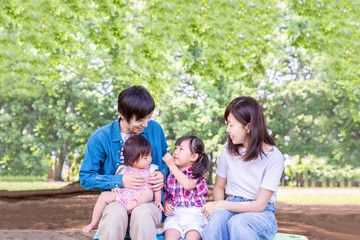 新緑の公園で遊ぶ家族4人。幸せ、愛情イメージ