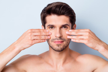 Close-up portrait of his he nice attractive bearded calm brown-haired guy touching cheeks applying...