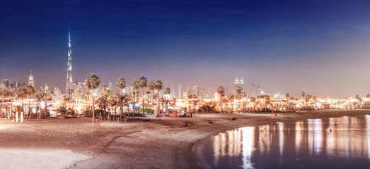 Landscape with deserted night beach and illuminated skyscrapers in the background in Dubai