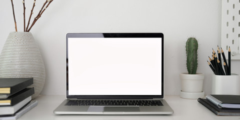 Close-up view of stylish workplace with open blank screen laptop computer and office supplies