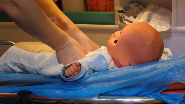 Close up of professional nurse performing CPR on child mannequin inside of ambulance van.