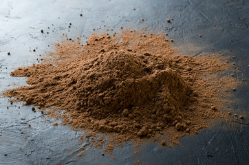 Closeup of cocoa powder heap on the black surface