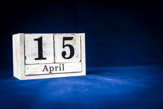 April 15th, Fifteenth of April, Day 15 of month April - rustic wooden white calendar blocks on dark blue background with empty space for text.
