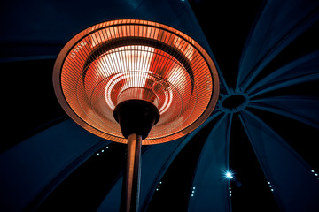 Infrared heater round shape on a black background in a large cold room. heating at night.