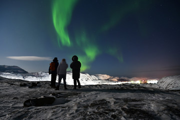 people admire the northern lights in the polar night in the Russian Arctic