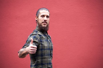 young man with beard and gauged pierced ears on red wall background