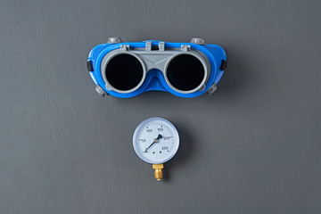 Blue goggles with double glass for protect eyes when welding near manometer for measuring pressure...