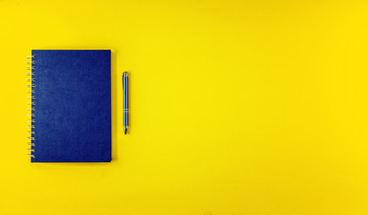 Flat lay top view blue notebook agenda with ballpoint pen on yellow background