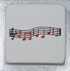 Happy Birthday music atop a square white cake.