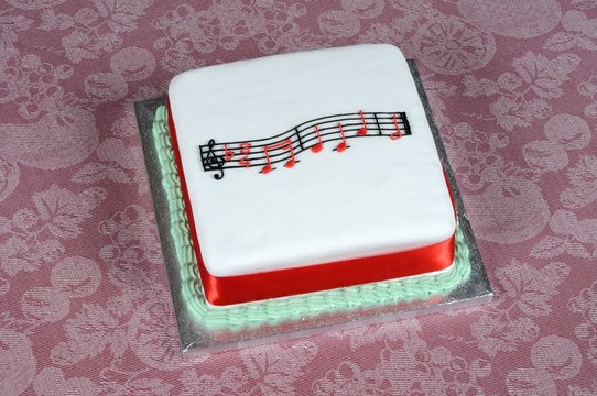 Happy Birthday music atop a square white cake.