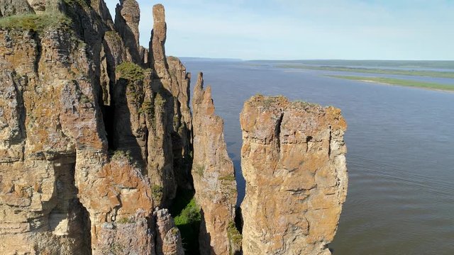 Aerial unique view close to Lena pillars stones sharp peaks rocks pattern covered moss lichen birds flying. Lone river cruise ship. Russia Siberia Travel landmark. Cinematic landscape national park
